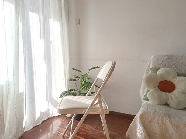 istock Empty white metal folding chair is situated in front of a large window 1498948829