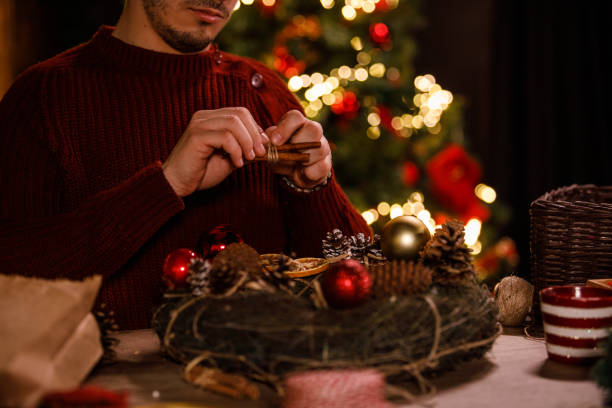 istock Young man tying a string around cinnamon sticks that he is about to use to decorate a Christmas wreath 1498948968