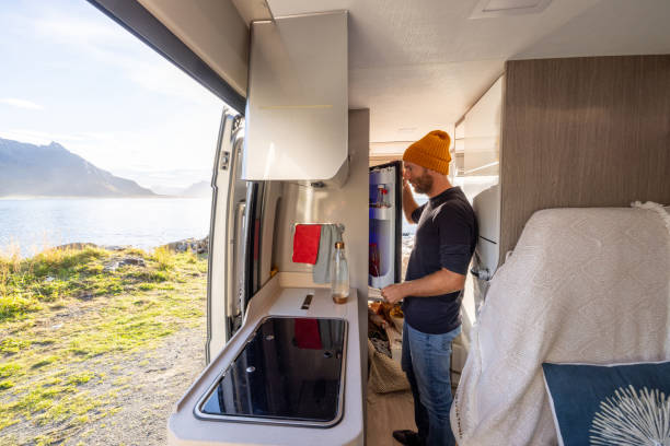istock Man cooking in a van, sea view. He opens the fridge 1498949209