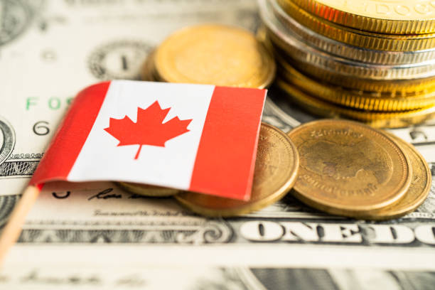 istock Stack of coins with Canada flag and US dollar banknotes. 1498949328