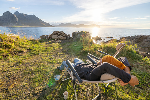 People travel, alternative homes concept. He looks at the beauty in nature. Sunset time by the sea, van life concept