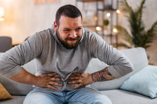 homme souffrant de douleurs sévères à l’estomac assis à la maison. - human large intestine photos et images de collection