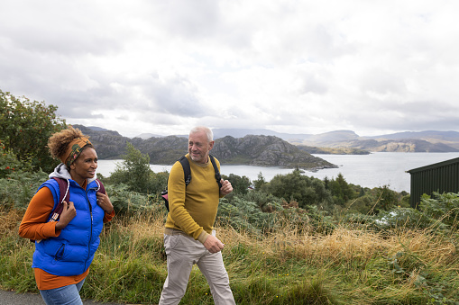A retired senior couple walking together around Loch Toridon in the Scottish highlands on an overcast day during summer.