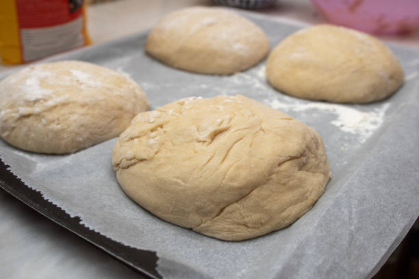 The process of baking at home. Close-up of sweet bread dough shaped into buns on a tray before going into the oven