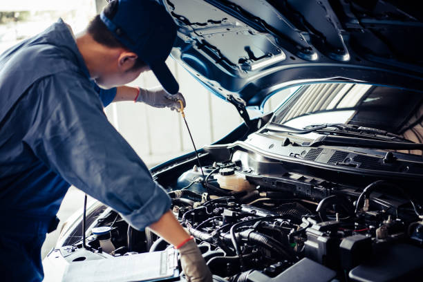 Car mechanic holding checking gear oil to maintenance vehicle by customer claim order in auto repair shop garage. Engine repair service. People occupation and business job. Automobile technician stock photo