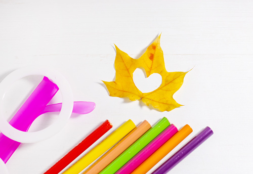 autumn fall leaves on paper with colorful pencils glasses frame mockup free space,hard sun light.hot tea,heart in middle of leaf.leaves hanging from rope with decorative pins clothes.back to school