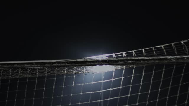Goal crossbar with net back side during soccer match at night. English football game. Flares and lights from the spotlight at the stadium. Sport concept. Close up