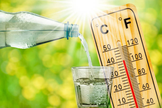 thermometer shows high temperature in summer heat and bottle with water with drinking glass stock photo