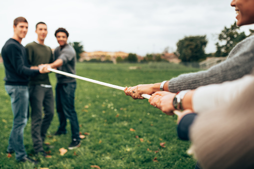 two hands hold a long rope against the background of a green lawn