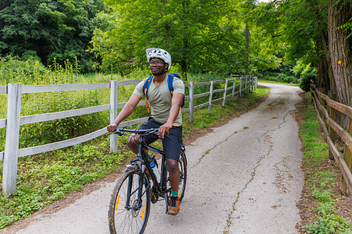 A young black mountain biker is riding a bicycle in the countryside.