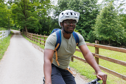 A young black mountain biker is riding a bicycle in the countryside.