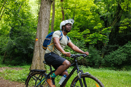 Young black cyclist rides a bicycle in a mountain forest.