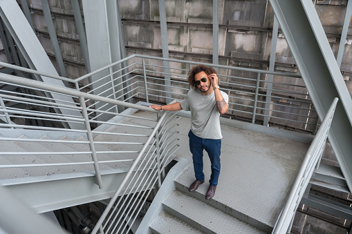 Young man with afro hair on the stairs in the city, cool urban fashion concept of a hipster guy with stylish