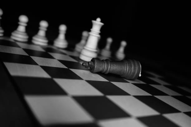 istock Black and white chess board with various pieces arranged in various positions, the king fallen 1498980674