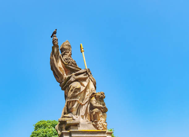 Old statue of st. Augustine of Hippo and gray crow on Charles Bridge in Prague, Czech Republic stock photo