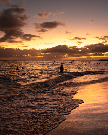 Incredible sunset at Waikiki Beach, Hawaii, USA. One womans silhouette standing in water.