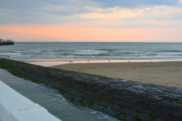 Sunset in June Belgian coast with on the side image the Staketsel pier in renovation with metal containers on the quay