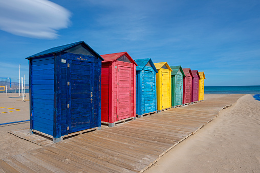 Town of Hastings, UK on the English Channel.  White and blue striped beach cabanas, owned by local citizens line the beach.