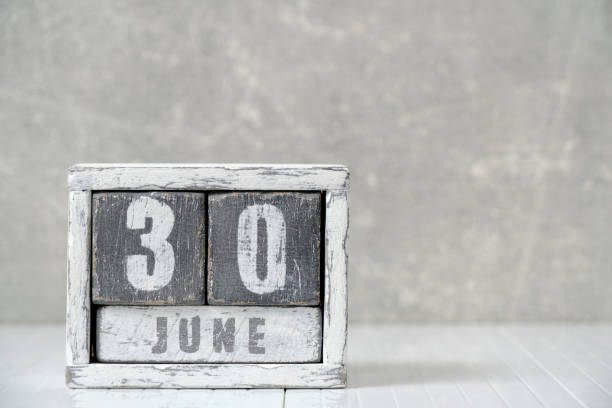 istock Calendar for June 30, made wooden cubes, against light concrete wall.With an empty space for your text. 1498986441