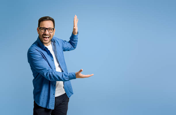 istock Cheerful businessman demonstrating something with copy space while standing on blue background 1498992721
