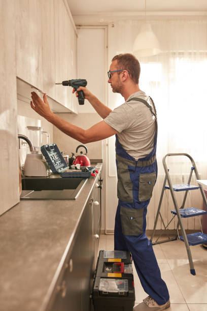 Handyman fixing kitchen cabinets in the apartment.