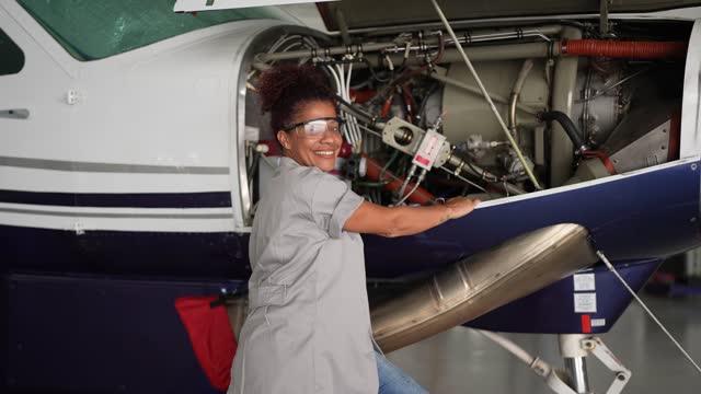Portrait of an female airplane mechanic repairing a airplane engine in the airport hangar