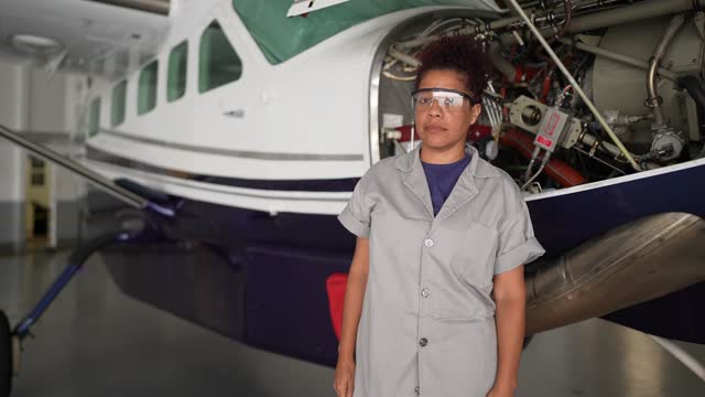 Portrait of an female airplane mechanic repairing a airplane engine in the airport hangar