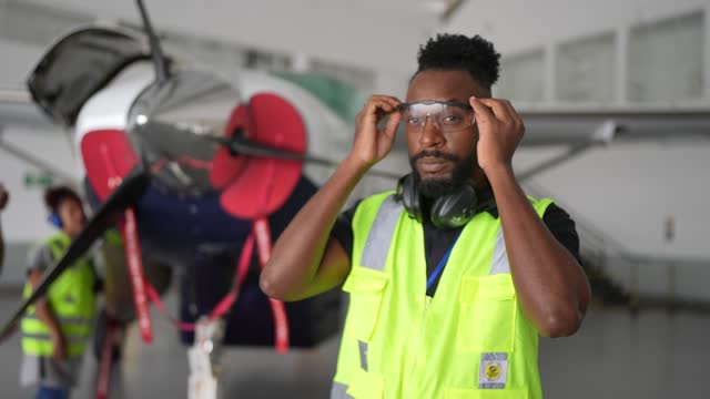 Portrait of an male airplane mechanic putting a work goggles in the airport hangar