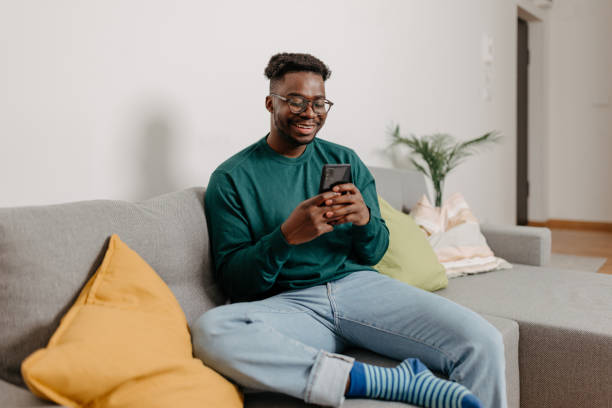 istock Young Man Grins with Delight as he Explores Endless Possibilities on his Mobile Phone 1498998522