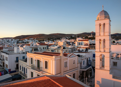 Tinos island Chora town Cyclades Greece. Last sunbeam colors Panagia Megalohari Orthodox Church Belfry and building around. Summer vacation