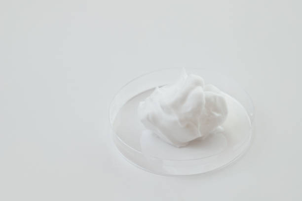 espuma cosmética blanca en placa de petri de laboratorio de vidrio sobre fondo blanco - chemistry white petri dish design fotografías e imágenes de stock