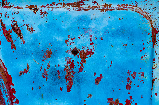 Blue Rusty Distressed Metal Textured Background - Metal detail showing scraped and textured blue paint along with rusty holes and red paint splatter.