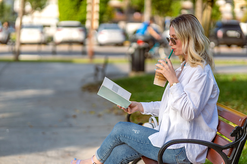 Woman sitting on park bench and reading a book