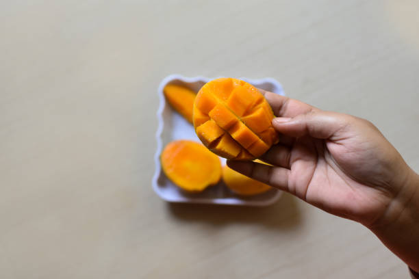 Perfect mango slice cut in cubes. Female hands holding fresh juicy mango. How to cut mango tutorial