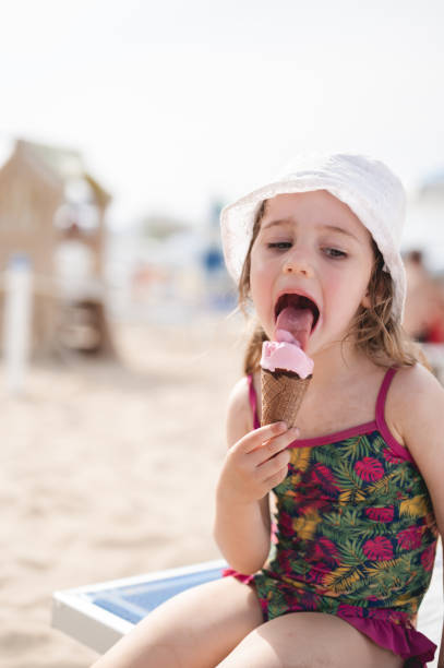 istock little girl licking ice cream on a beach. 1499010899