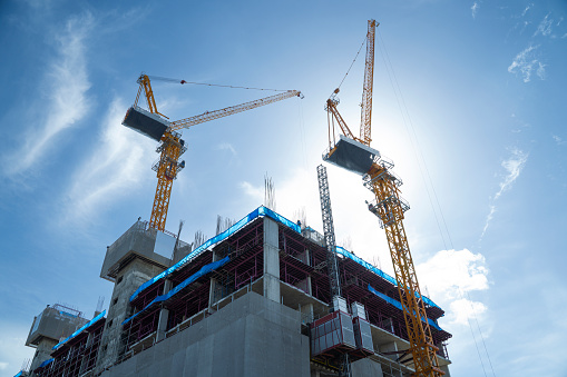 several construction tower cranes of different heights at a building site during the construction of blocks of flats, view against the sky