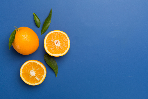 Flat lay with fresh oranges and leaves on color background