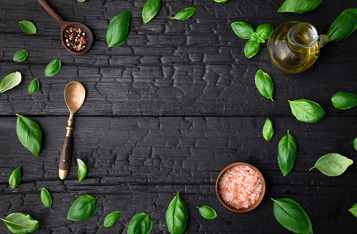 fresh basil leaves on dark background with spices and space for text