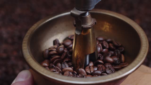 Vintage traditional manual coffee grinder. Wood and copper. Coffee beans, cinnamon, spices at dark background. Camera rotating around autentic coffee machine.
