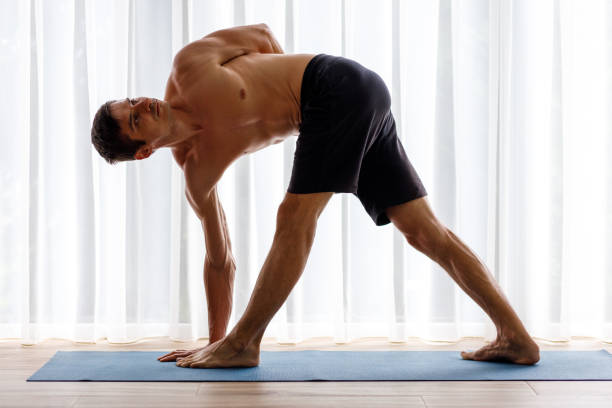 istock Young man doing triangle yoga pose in the morning 1499021340