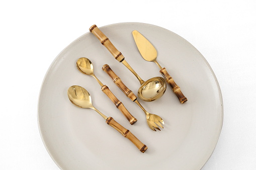 golden cutlery with bamboo seen from above on ceramic plate