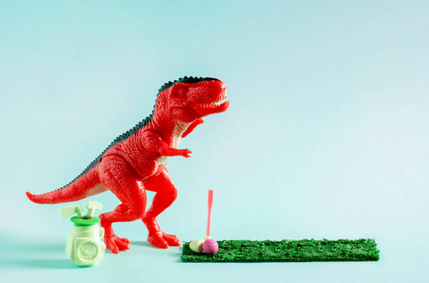 istock Cute red toy dinosaur playing mini golf on blue background. 1499028603