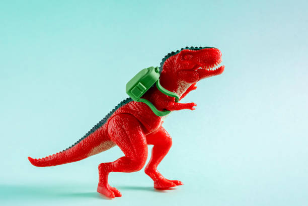 istock Red toy dinosaur carry green backpack on blue background. 1499028606