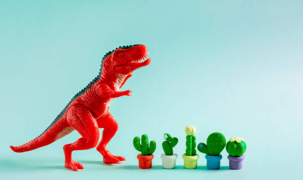 istock Cute greeting card with red dinosaur and cacti on blue background. Creative gardening concept 1499028657