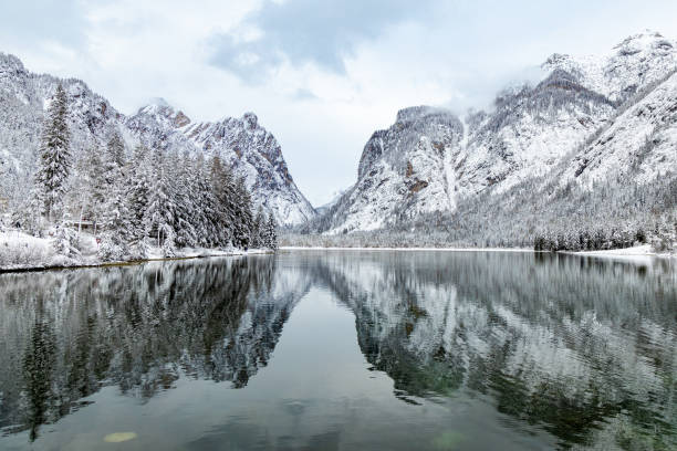 bela vista de toblacher see (lago dobbiaco) em um dia de inverno nevado. reflexos de montanhas e árvores sobre a água; dolomitas - val pusteria - fotografias e filmes do acervo