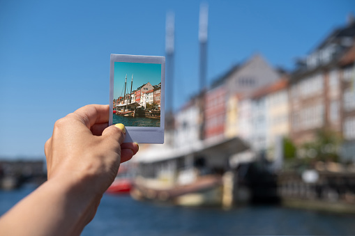 A hand holding an instant camera photo of Copenhagen.