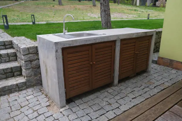 Photo of Concrete table with sink and water tap. Outdoor concrete table.