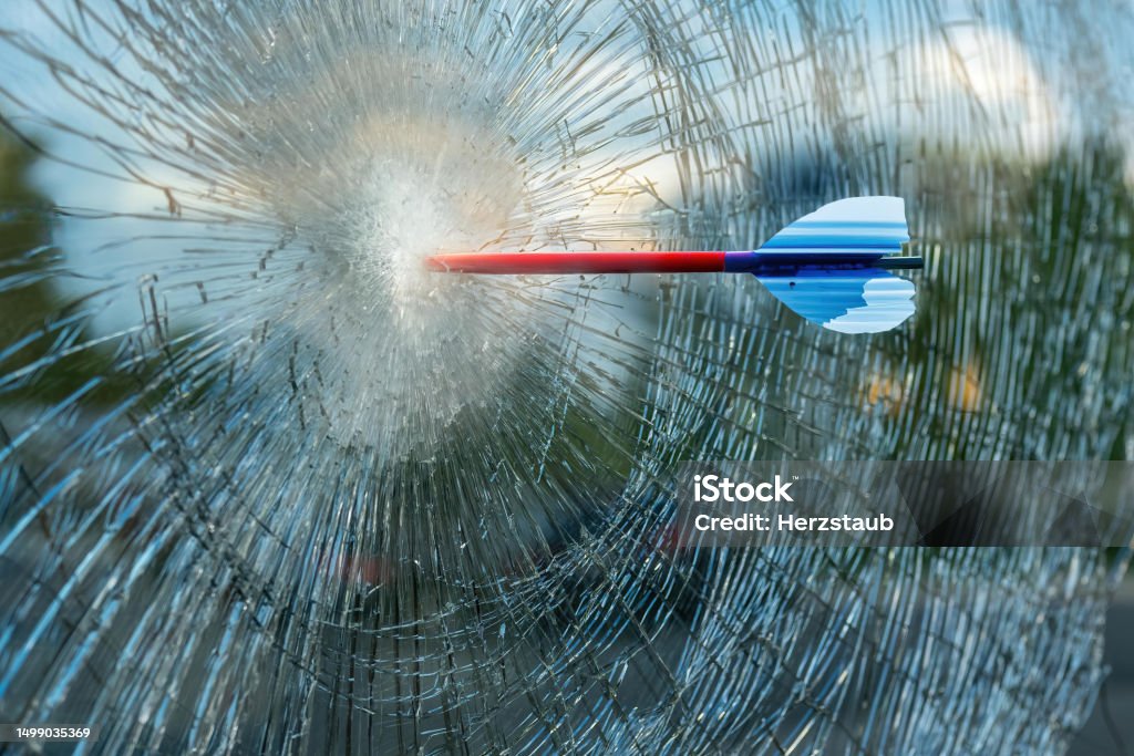 arrow in a window with broken glass an arrow in a window with broken glass Abstract Stock Photo