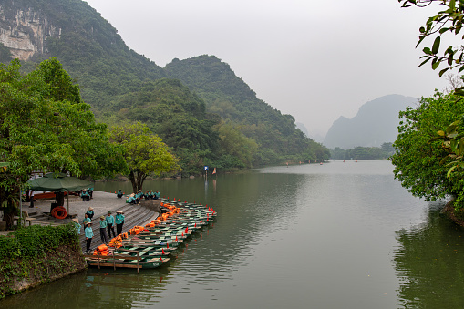 Ninh Binh, Vietnam-April 2023; High angle view of sampan rowing boats for tourists on cave tours on Red River Delta in landscape of Trang An between forested limestone mountains (Halong Bay on land)
