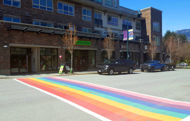 Rainbow Crosswalk Small Town Pemberton British Columbia Pemberton, British Columbia, Canada- June 16, 2023: Rainbow flag painted crosswalk painted on major street in Pemberton. Modern apartment and business building in background. pemberton town stock pictures, royalty-free photos & images